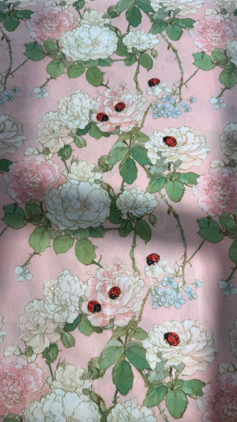 Close-up of Primrose cotton satin fabric showing roses, greenery and tiny ladybugs