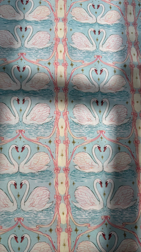 Close-up of Odette cotton satin fabric showing swans, ribbons and gold details on aqua