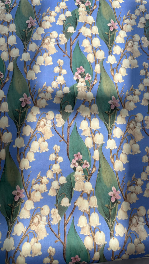 Close-up of Lillia cotton satin fabric showing lily of the valley stems and green leaves
